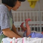 На этой фотографии, сделанной 24 мая 2017 года, изображен социальный работник, ухаживающий за ребенком в общинной церкви Джусаранг на юге Сеула. Юнг Ён-Дже/AFP/Getty Images