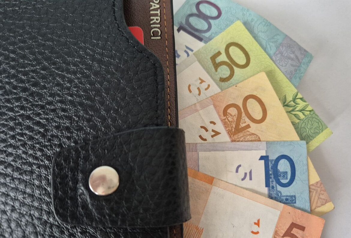 Бумажник с купюрами разного номинала, частично выглядывающими наружу.