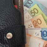 Бумажник с купюрами разного номинала, частично выглядывающими наружу.