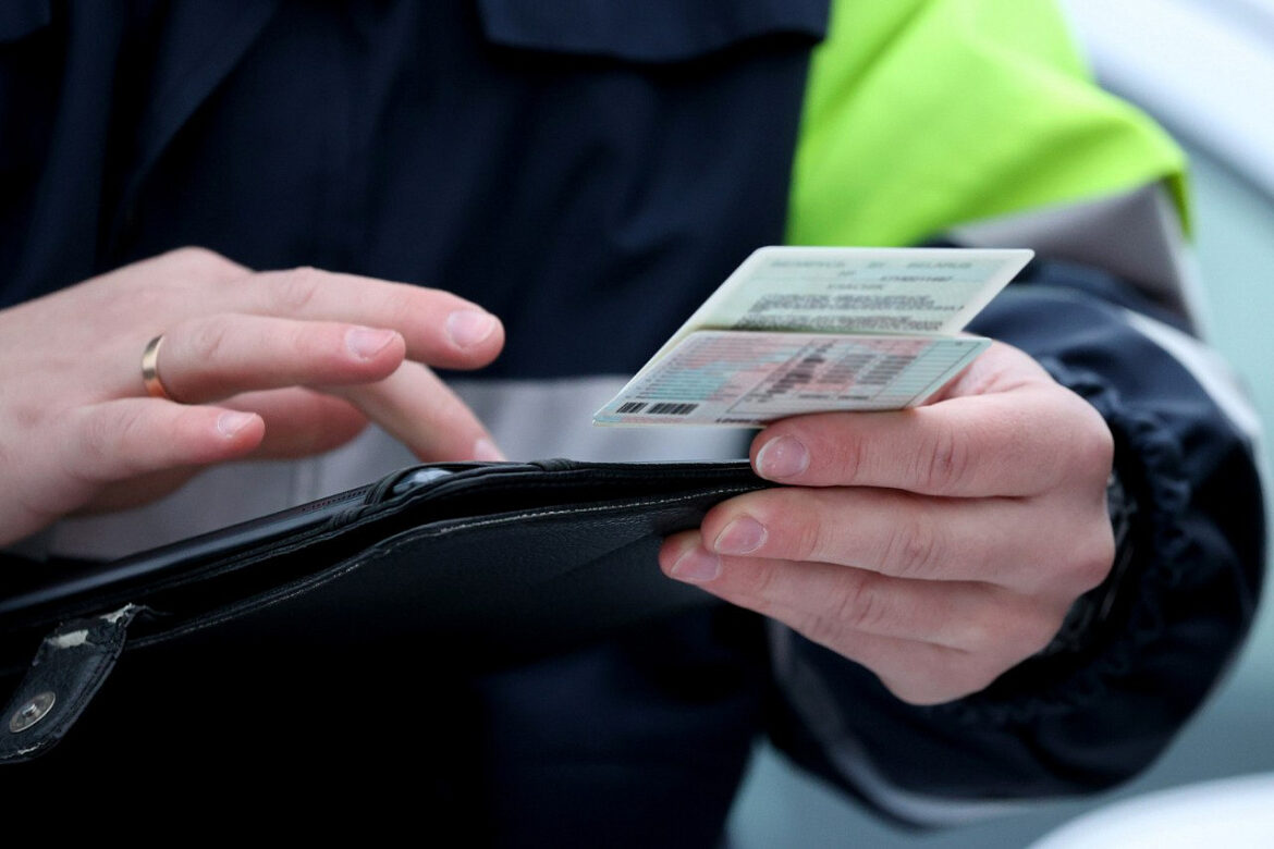 В Глуске задержали водителя, который даже не учился в автошколе Инспектор ГАИ держит в руках водительское удостоверение и проверяет его подлинность.