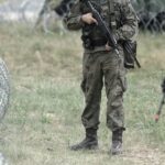 Польские солдаты в камуфляже на фоне колючей проволоки на границе с Беларусью.