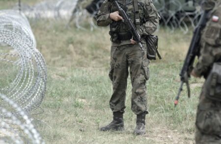 Польские солдаты в камуфляже на фоне колючей проволоки на границе с Беларусью.