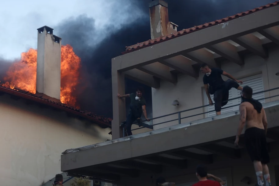 Люди спасаются из дома на балконе, рядом бушует пламя и поднимается густой чёрный дым