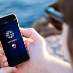 Человек держит смартфон с включённым экраном, на котором отображается надпись «Роуминг: off».