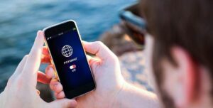 Человек держит смартфон с включённым экраном, на котором отображается надпись «Роуминг: off».