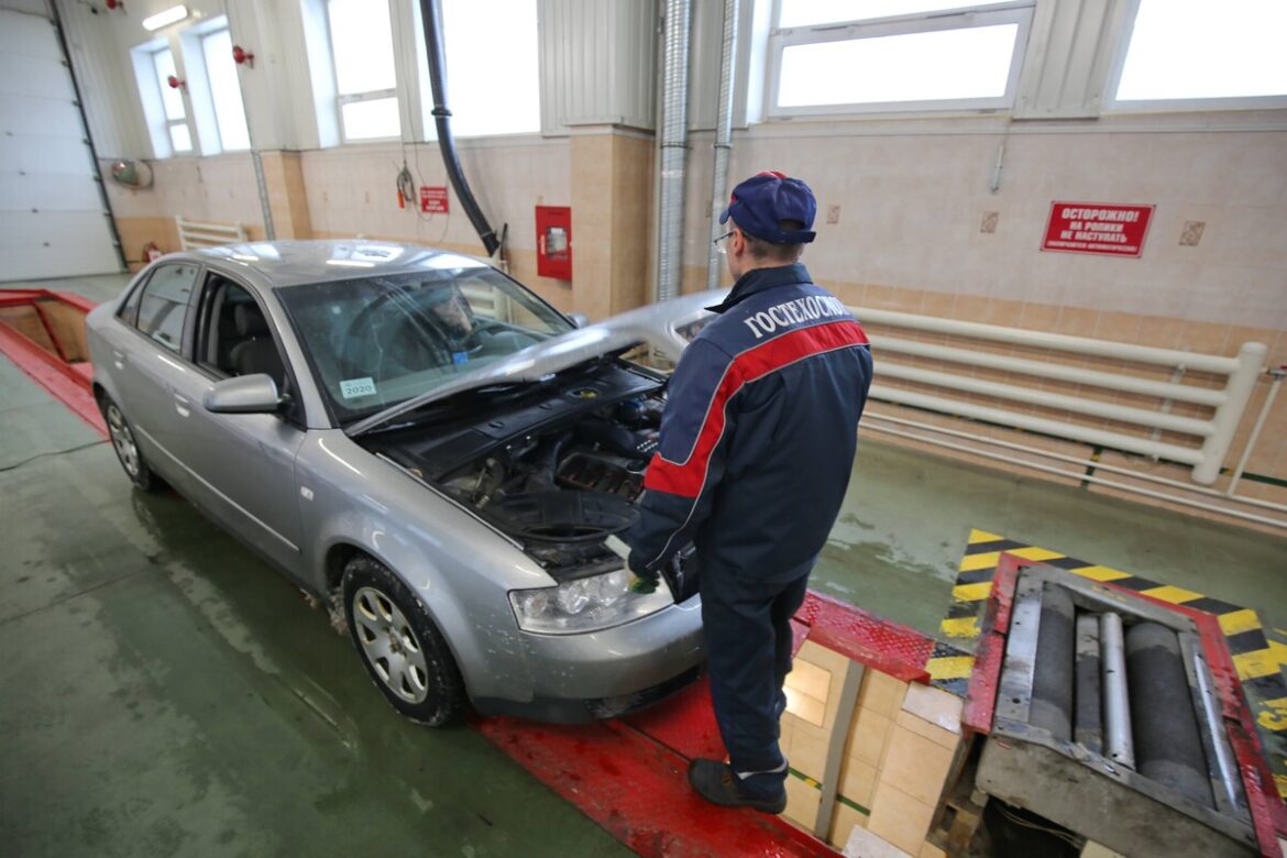 В Беларуси дорожает техосмотр: сколько теперь стоит пройти ТО Сотрудник в форме "Гостехосмотра" осматривает автомобиль на станции технического осмотра – капот открыт, машина стоит у смотровой ямы в помещении.