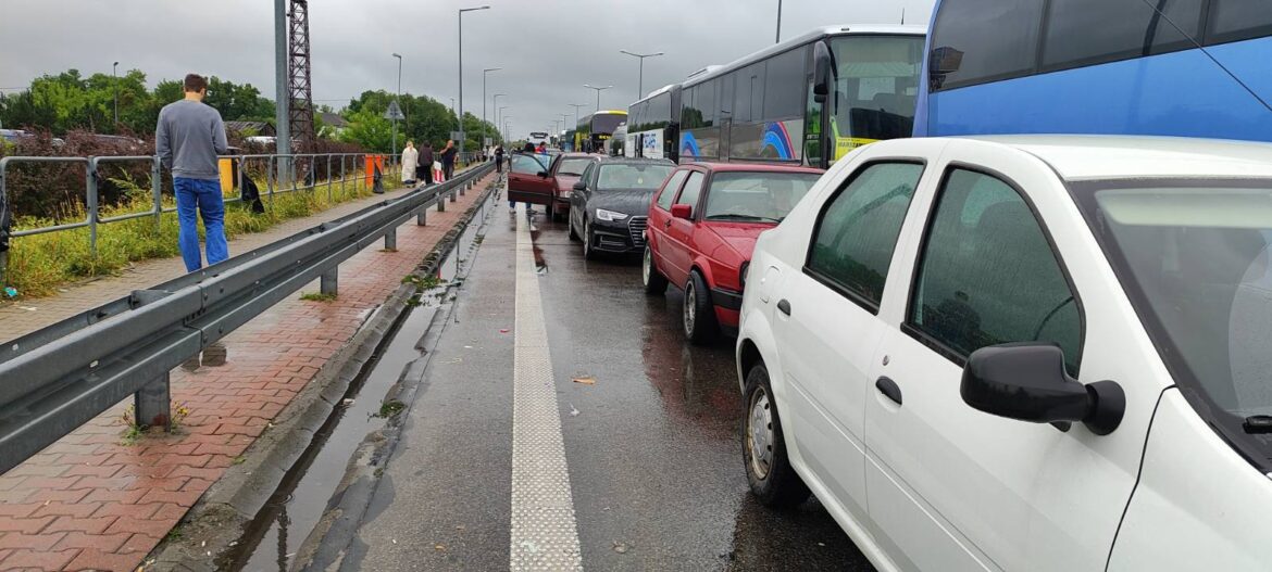 Легковые автомобили и туристические автобусы стоят в очереди на пропускном пункте в дождливую погоду