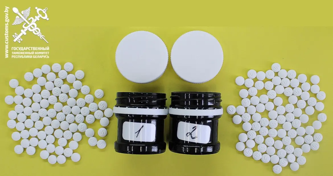 Фото белых таблеток, высыпавшихся из двух чёрных банок