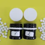 Фото белых таблеток, высыпавшихся из двух чёрных банок