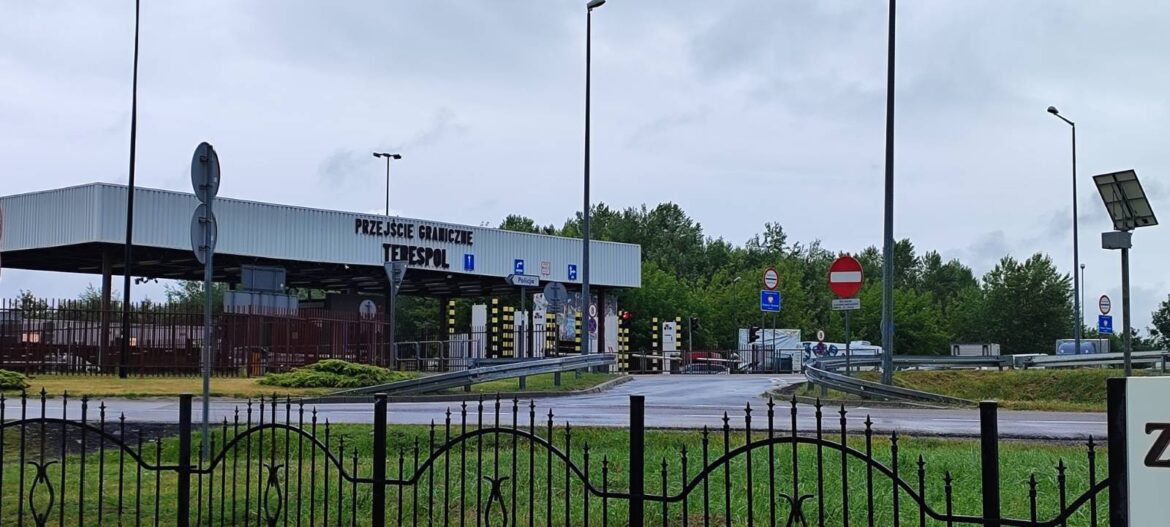 Здание пункта пропуска Тересполь на границе Польши и Беларуси, видны шлагбаумы, знаки и грузовики на фоне пасмурного неба