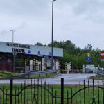 Здание пункта пропуска Тересполь на границе Польши и Беларуси, видны шлагбаумы, знаки и грузовики на фоне пасмурного неба