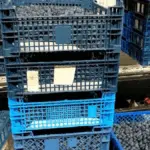 штабеля синих пластиковых ящиков, заполненных ягодами голубики, рядом с фургоном.