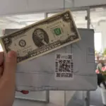 Настоящие доллары, купюра 2 доллара США на фоне фирменного пакета Wildberries в руках