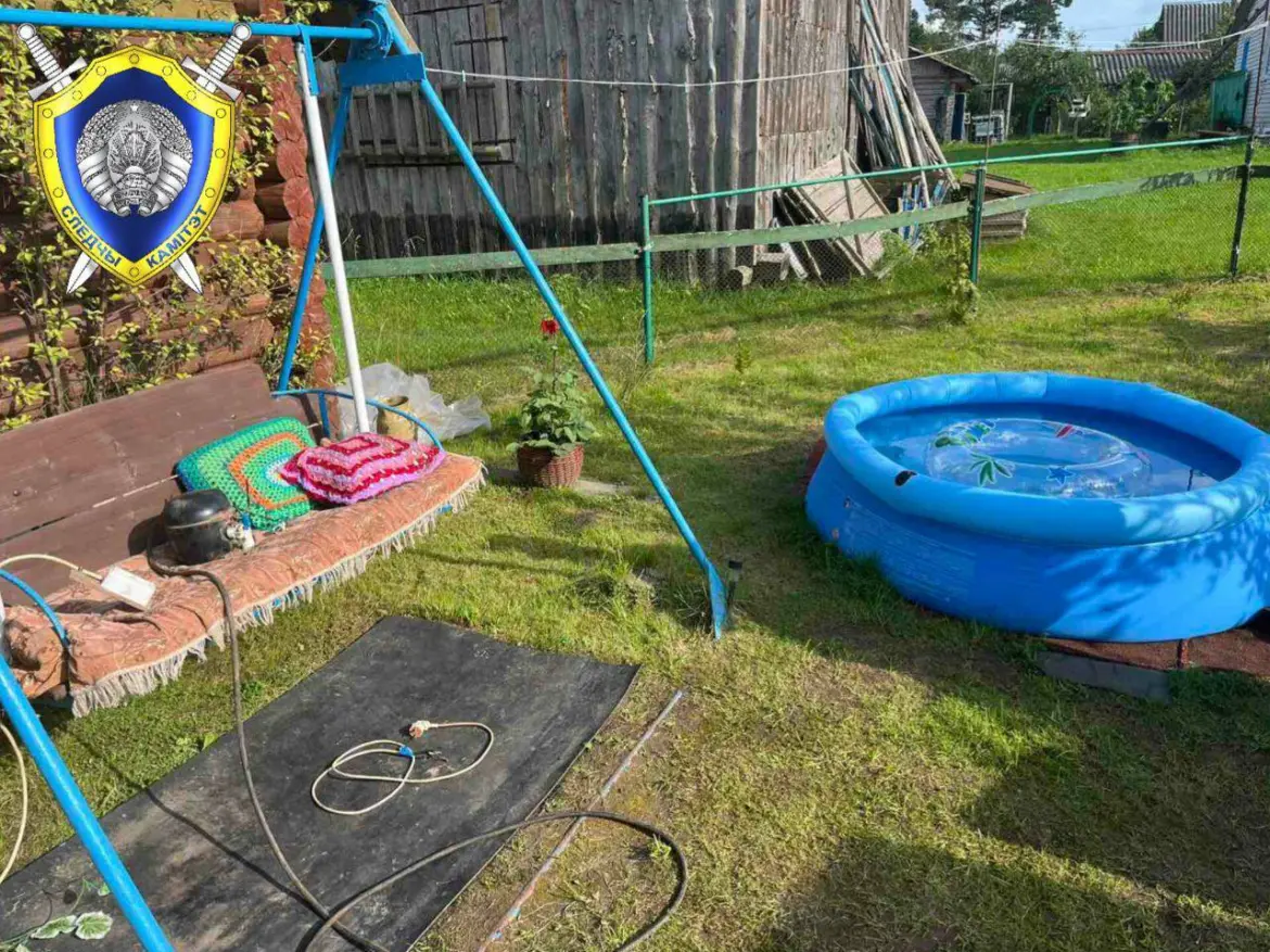 На фото двор частного дома: у стены стоит скамейка с компрессором и удлинителем, рядом расстелен коврик, чуть дальше – надувной бассейн