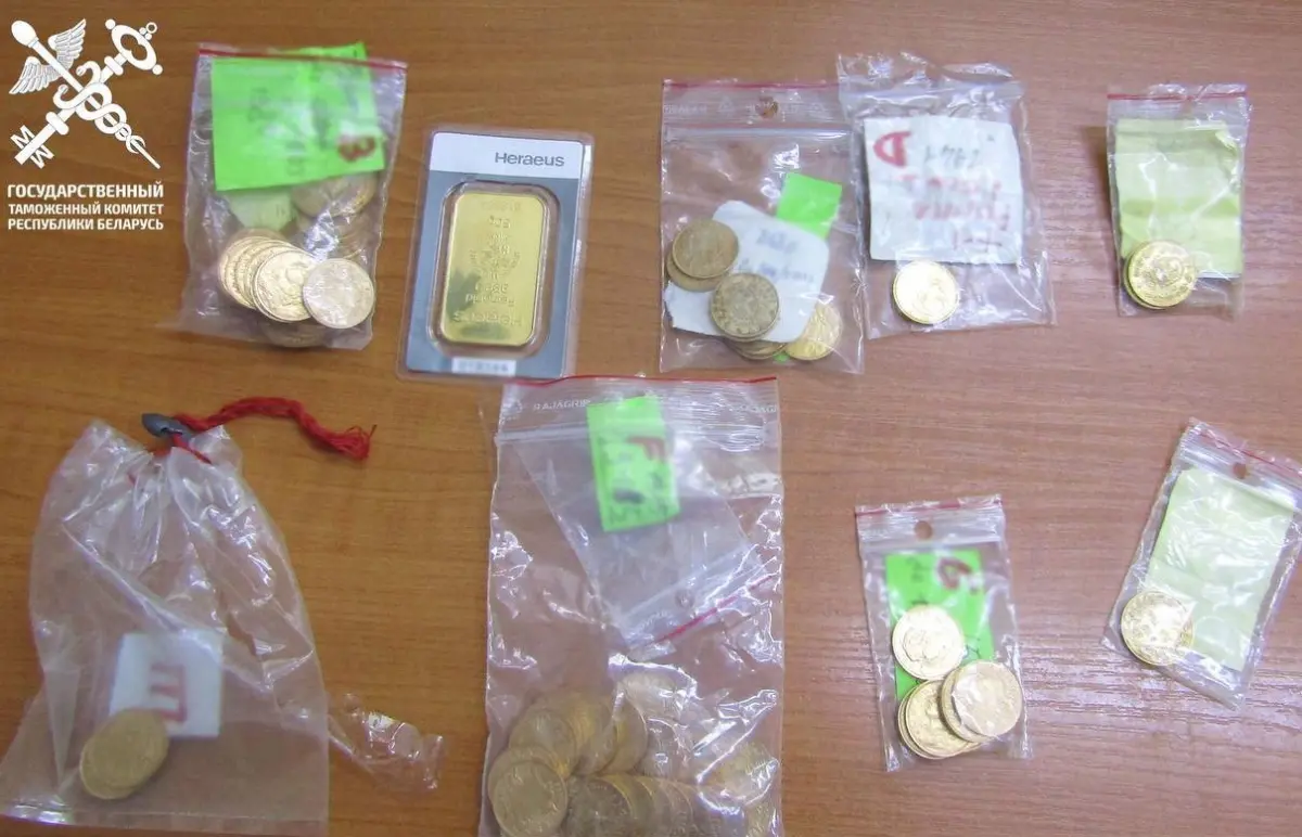 Изъятые таможней золотые монеты и слиток в пакетах на столе.