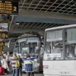 Минский автовокзал, автобусы на платформе и пассажиры с багажом в ожидании рейса в Вильнюс.