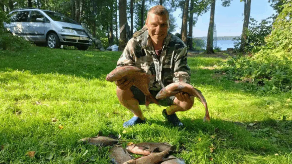 улыбающийся рыбак в камуфляжной куртке держит двух лещей