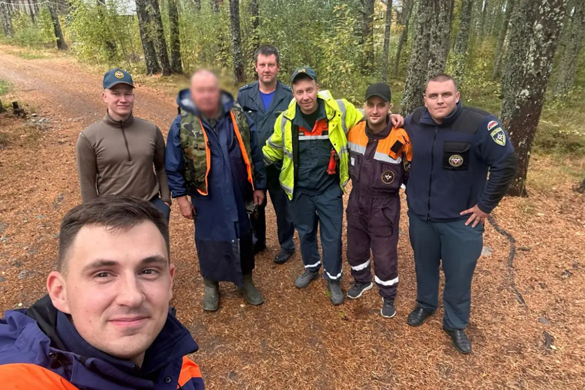 группа спасателей и найденный рыбак позируют для фото в лесу после завершения поисков*