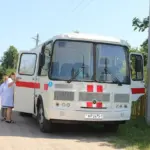 белый автобус-передвижной ФАП с красными крестами, возле него врачи в белых халатах