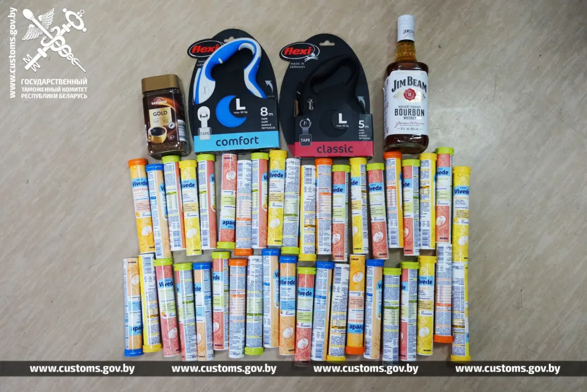 разложены изъятые товары - тюбики витаминов, банка кофе, бутылка виски и два поводка для собак