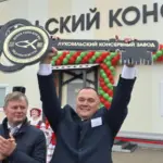 Мужчина поднимает символический ключ на открытии Лукомльского консервного завода