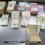 крупные стопки купюр номиналом 100, 200, 500 и 1000 гривен, разложенные на металлическом столе в таможне.