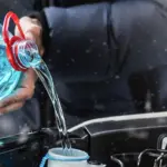 Крупная пластиковая канистра с синей незамерзающей жидкостью, которую заливают в подкапотное пространство автомобиля зимой.