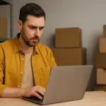 Предприниматель за ноутбуком на фоне коробок