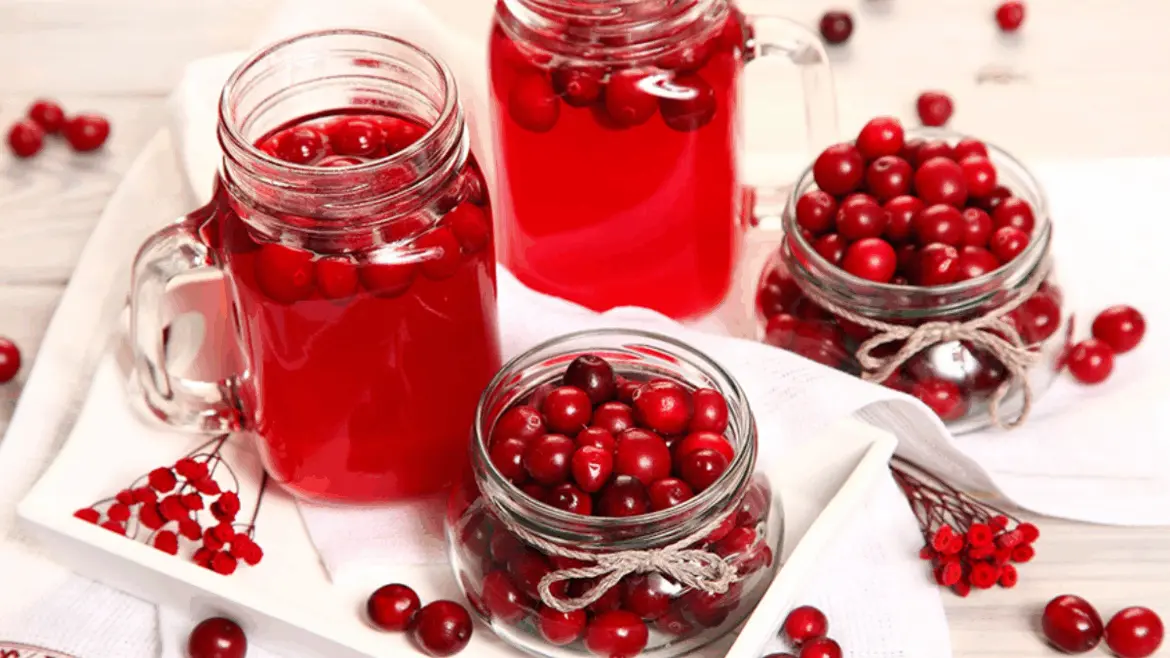 Стаканы и банки с клюквенным морсом и свежими ягодами
