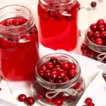 Стаканы и банки с клюквенным морсом и свежими ягодами