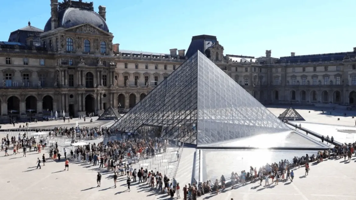 Люди стоят в очереди у пирамиды Лувра в Париже