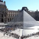 Люди стоят в очереди у пирамиды Лувра в Париже