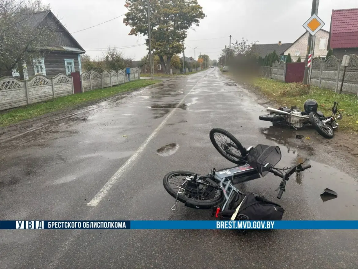 место аварии в деревне Язвинки: на асфальте лежат мотоцикл и электровелосипед, видно следы торможения и мокрую дорогу.