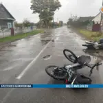 место аварии в деревне Язвинки: на асфальте лежат мотоцикл и электровелосипед, видно следы торможения и мокрую дорогу.