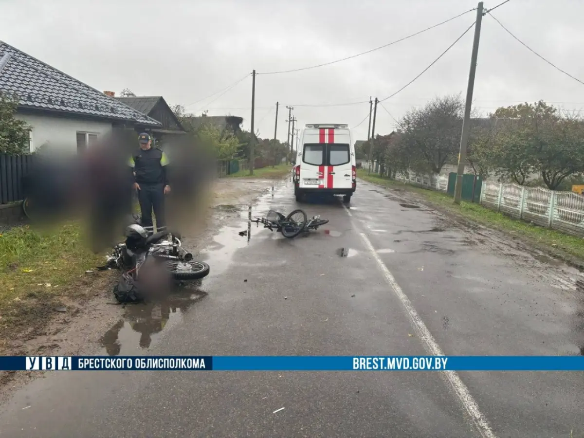 автомобиль скорой помощи и инспектор ГАИ возле мотоцикла и электровелосипеда на мокрой дороге после аварии.