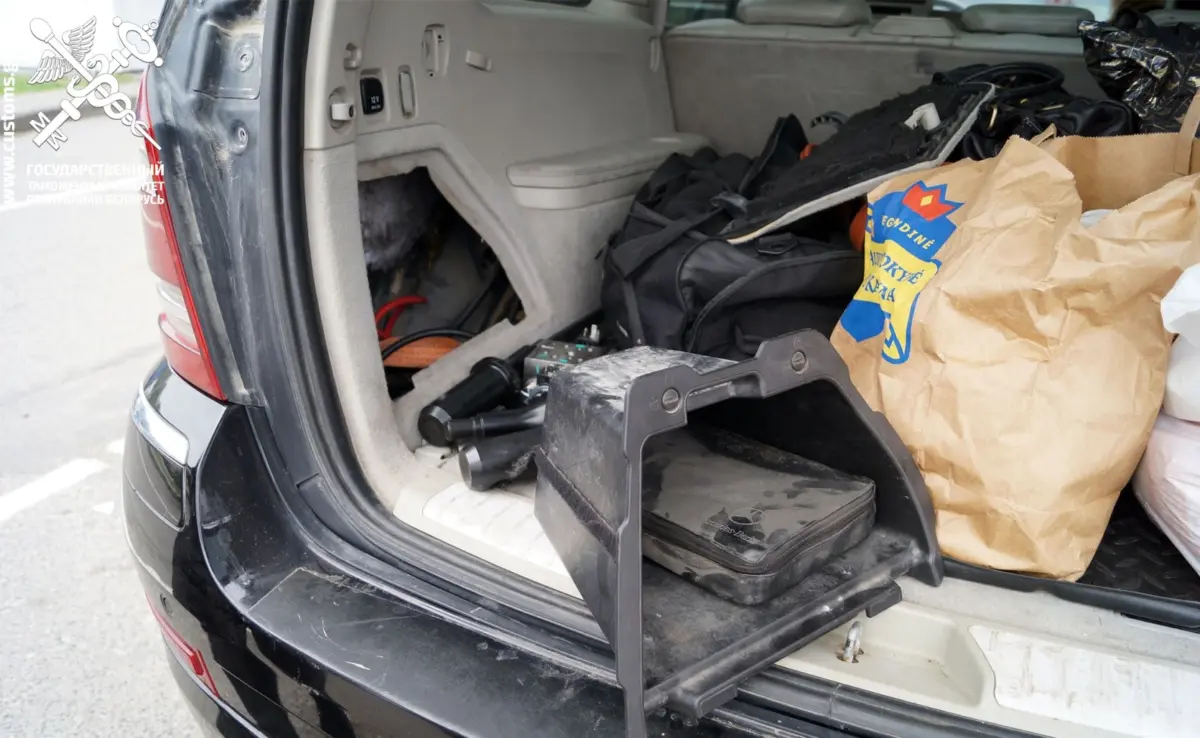 багажник автомобиля с разобранной обшивкой, внутри видны спрятанные детали и инструменты.