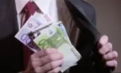 крупный план руки мужчины в деловом костюме, держащего банкноты евро и прячущего их во внутренний карман пиджака, банкрот
