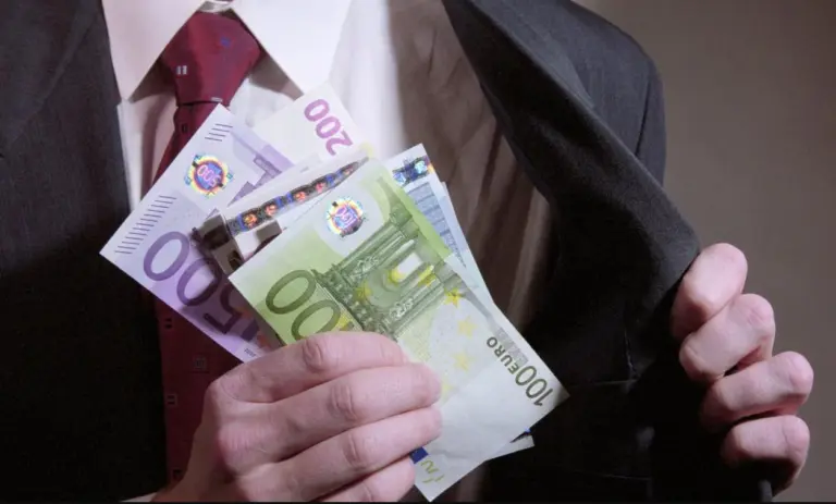 крупный план руки мужчины в деловом костюме, держащего банкноты евро и прячущего их во внутренний карман пиджака, банкрот