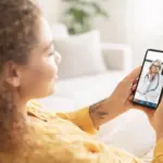Женщина держит смартфон и общается с врачом по видеосвязи через медицинское приложение